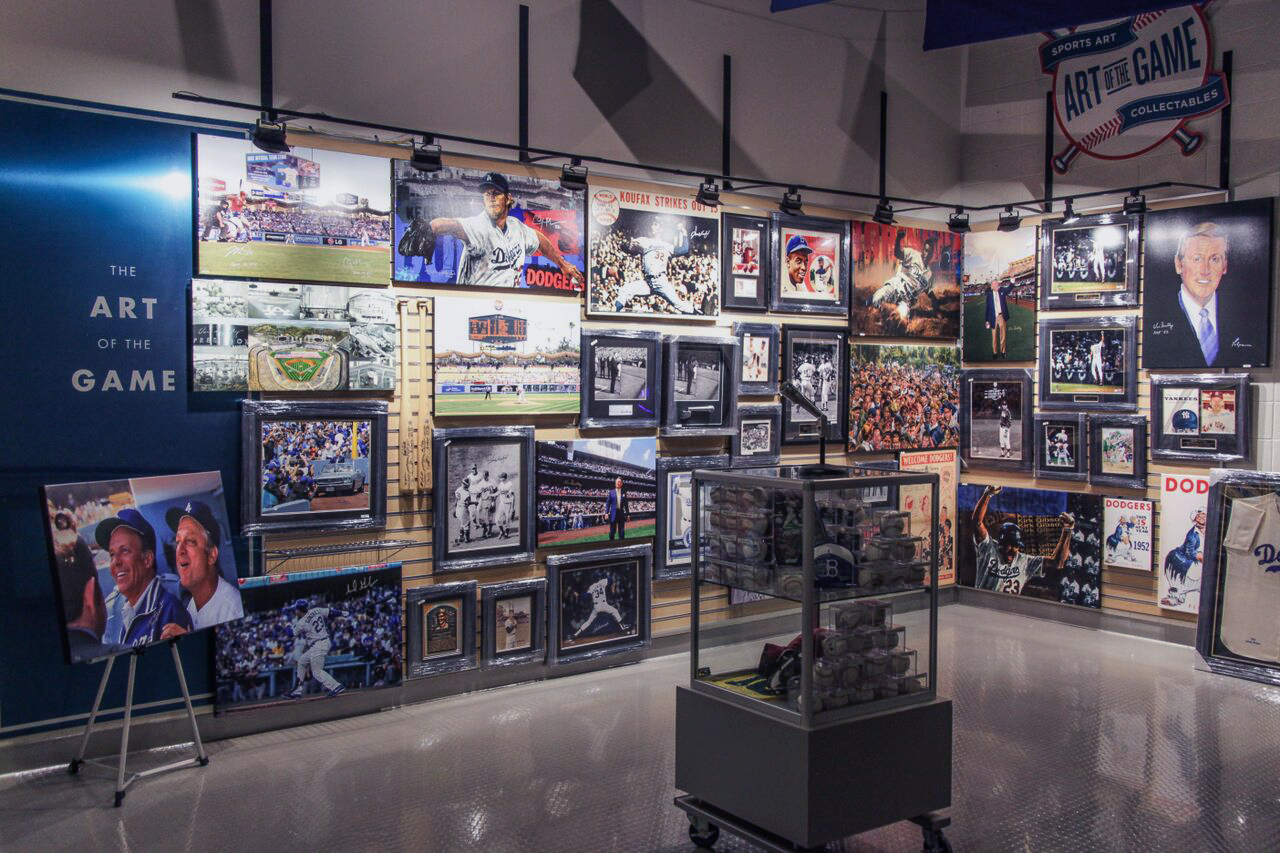 A display case in front of a wall of Dodger Stadium sports art.