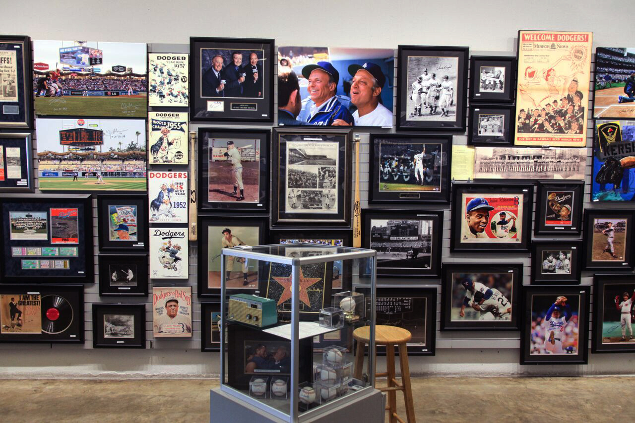 Sports art on the wall in front of a display case.